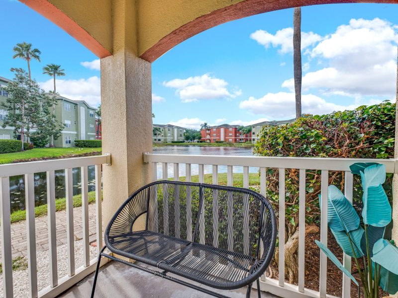 Balcony view of pond, palm trees, and apartments at TGM University Park.