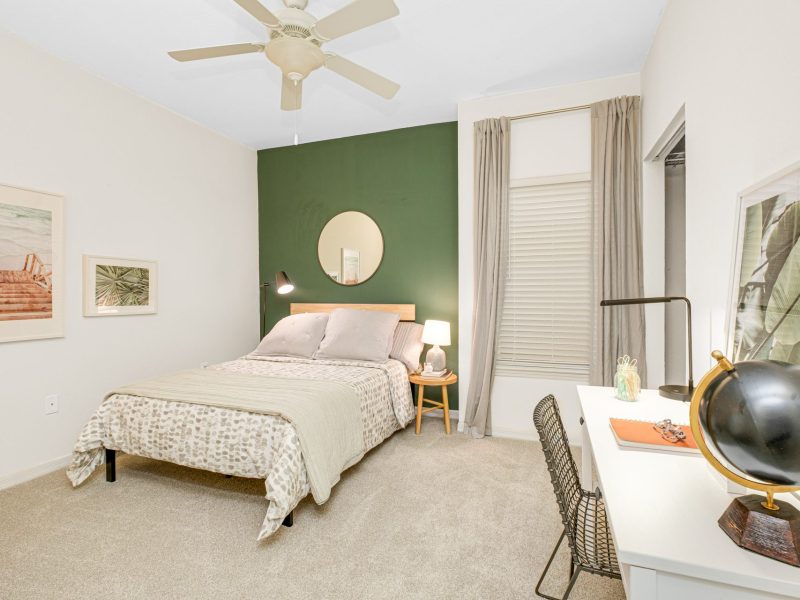 Modern bedroom with green accent wall at TGM University Park Apartments.