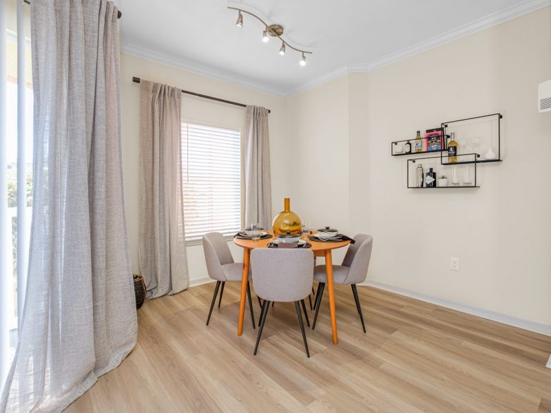 Modern dining room with round wooden table and gray chairs at TGM University Park.