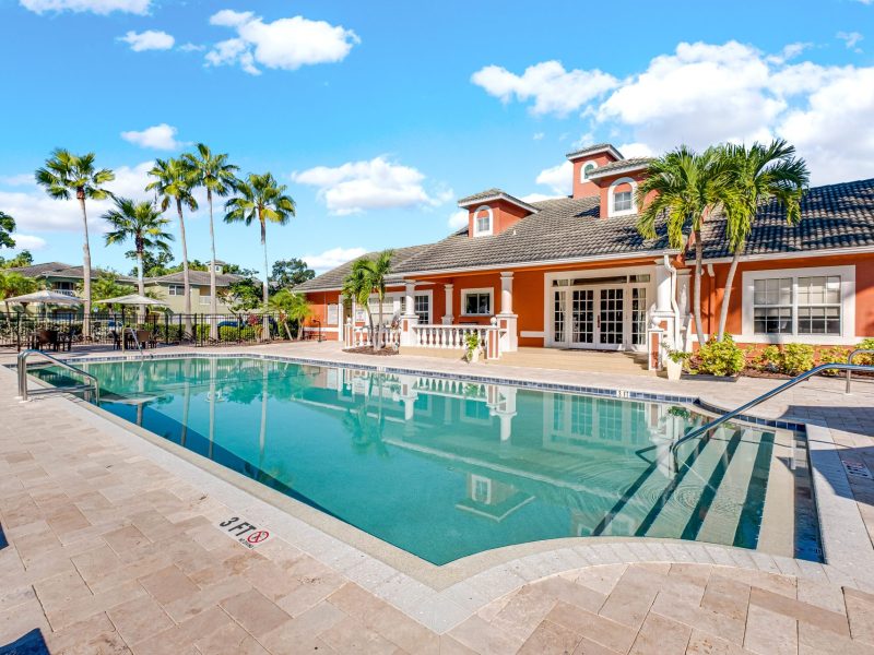 Luxury resort-style poolside at TGM University Park with palm trees and modern architecture.