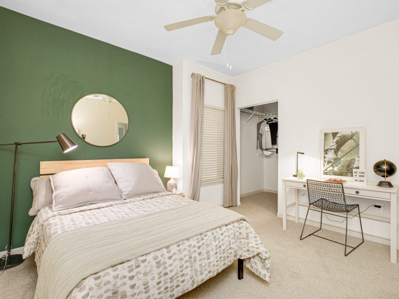 Modern bedroom with green accent wall and cozy decor at TGM University Park.