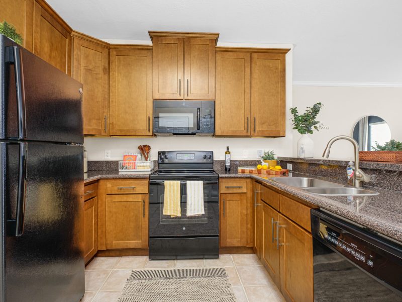 Modern kitchen with wooden cabinets and granite countertops at TGM University Park.