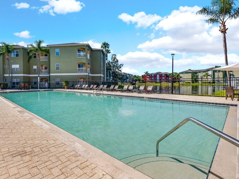 Luxury swimming pool with lounge chairs at TGM University Park residential community.