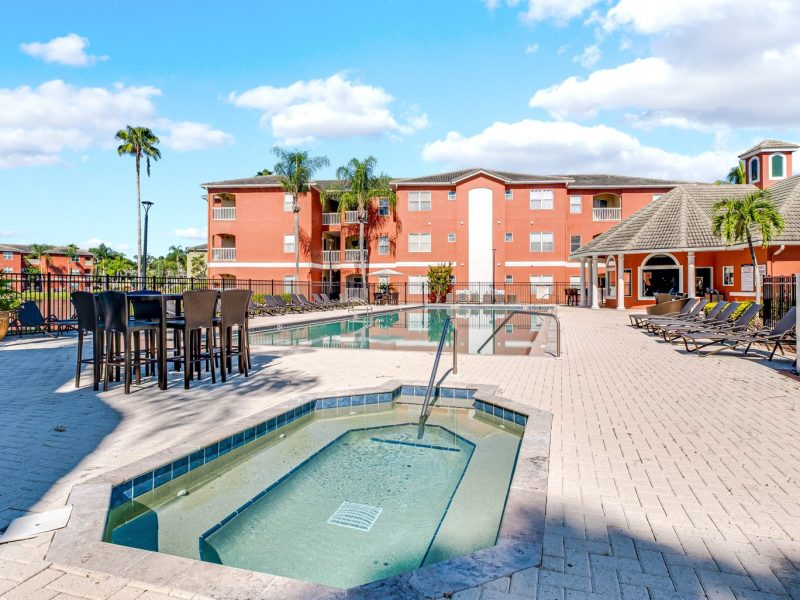 Luxury pool and hot tub area at TGM University Park apartments with palm trees.