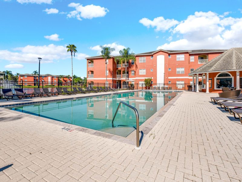 Resort-style swimming pool with lounge chairs at TGM University Park apartments.