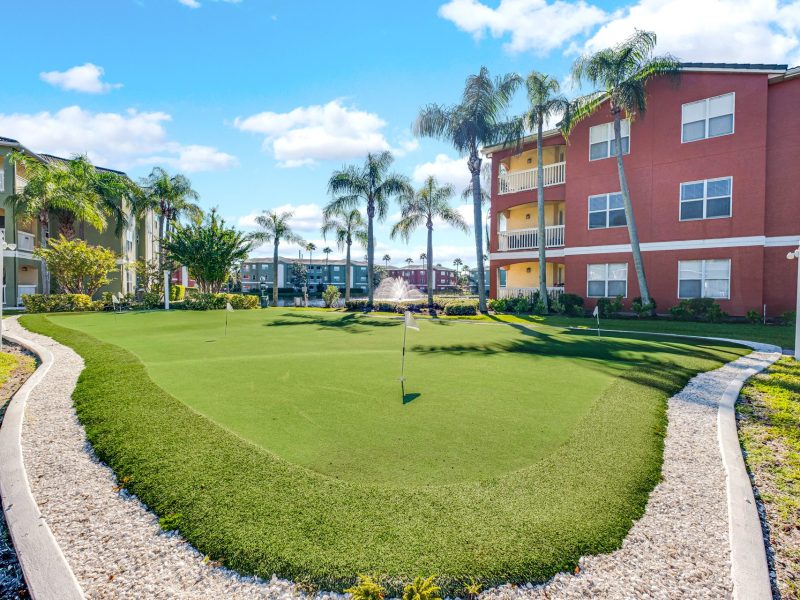 Outdoor putting green and landscaped courtyard at TGM University Park apartments.